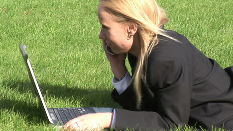 Woman-lying-on-grass-using-laptop-computer