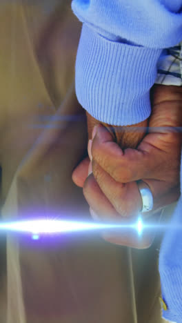 Animation-of-light-moving-over-midsection-of-senior-couple-walking-holding-hands