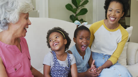 Portrait-of-happy-african-american-grandmother-with-adult-daughter-and-granddaughters-in-living-room