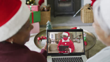 Diverse-senior-female-friends-using-laptop-for-christmas-video-call-with-santa-on-screen