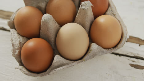 Video-of-close-up-of-brown-eggs-in-egg-carton-on-rustic-background