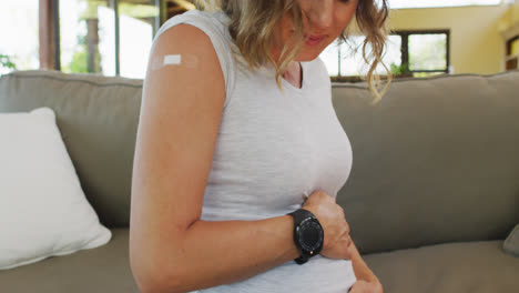 Happy-caucasian-woman-touching-belly-and-looking-at-plaster-after-vaccination