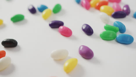 Video-of-close-up-of-multi-coloured-sweets-spinning-over-white-background