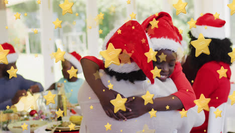 Yellow-stars-falling-against-african-american-girl-hugging-her-grandmother-at-home-during-christmas
