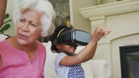 Glückliche-Afroamerikanische-Großmutter-Mit-Enkelinnen-Mit-VR-Headset-Im-Wohnzimmer