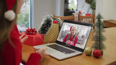 Caucasian-woman-on-laptop-video-call-with-happy-female-friend-at-christmas-time
