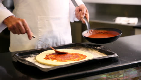 Koch-Verteilt-Soße-Auf-Einer-Pizza