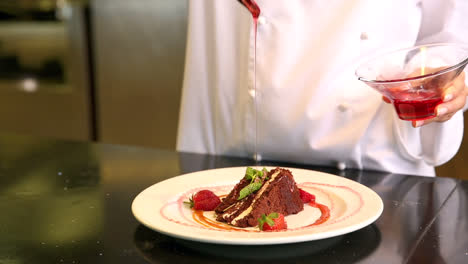 Chef-pouring-strawberry-sauce-over-chocolate-cake