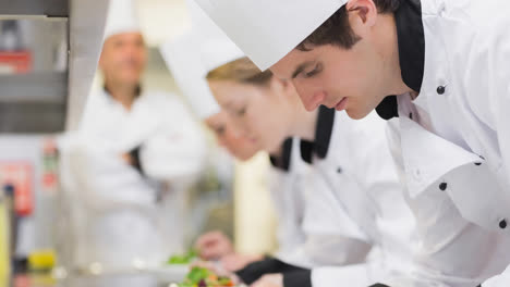 Focused-young-caucasian-male-chef-preparing-food-in-professional-kitchen