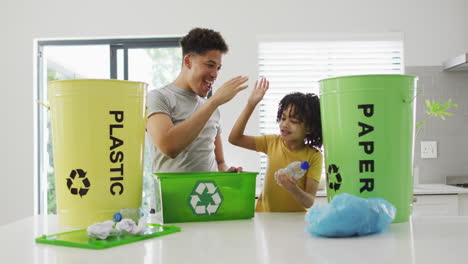 Biracial-father-and-son-recycle-at-home,-with-copy-space