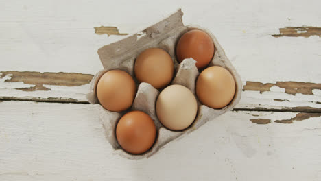 Video-of-overhead-view-of-brown-eggs-in-egg-carton-on-rustic-background