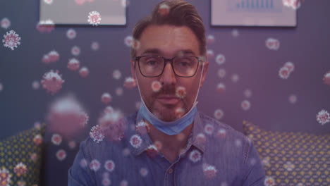 Animation-of-virus-cells-floating-over-caucasian-businessman-with-face-mask-talking-in-office