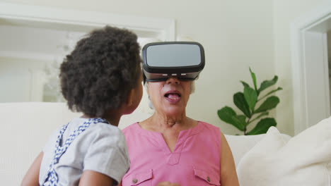 Happy-african-american-grandmother-using-vr-headset-with-granddaughter-in-living-room