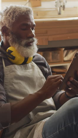 Afroamerikanischer-Handwerker-überprüft-Pläne-Auf-Einem-Tablet-In-Einer-Werkstatt