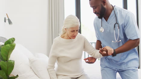 Young-African-American-male-nurse-assists-senior-Caucasian-woman-at-home