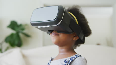 Smiling-african-american-girl-playing-with-vr-headset-in-living-room