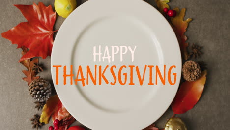 Animation-of-happy-thanksgiving-text-over-plate-and-leaves-on-grey-background
