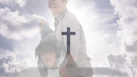 Animation-of-crucifix-cross-monument-and-cloudy-sky-over-biracial-father-playing-with-son