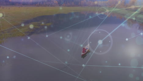 Animation-of-network-of-connections-and-light-spots-against-aerial-view-of-man-riding-boat-in-a-lake