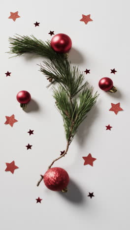 Vertical-video-of-fir-tree-branch-with-christmas-decorations-and-copy-space-on-white-background