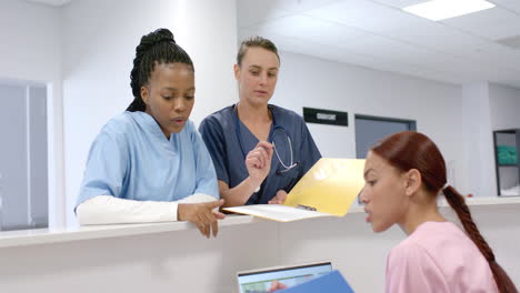 Junge-Afroamerikanische-Und-Kaukasische-Mitarbeiter-Des-Gesundheitswesens-überprüfen-Dokumente-In-Einem-Krankenhaus