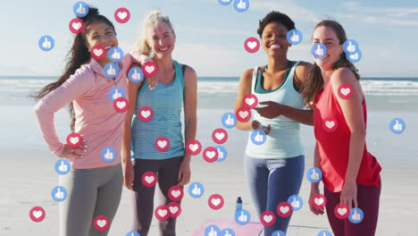 Animation-of-social-media-icons-over-group-of-diverse-fit-women-smiling-together-at-the-beach