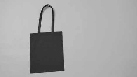 Nahaufnahme-Einer-Schwarzen-Tasche-Auf-Grauem-Hintergrund,-Mit-Kopierraum,-Zeitlupe