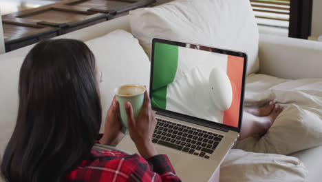 Biracial-woman-watching-laptop-with-rugby-ball-on-flag-of-ivory-coast-on-screen