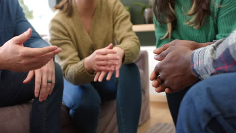 Diverse-group-of-friends-holding-hands-in-group-therapy-session