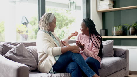 Happy-african-american-senior-mother-and-daughter-sitting-on-couch-and-embracing,-slow-motion