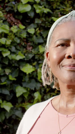 Halbes-Gesicht-Einer-Glücklichen-Afroamerikanischen-Seniorin,-Die-Im-Sonnigen-Garten-Steht-Und-Lächelt,-Zeitlupe