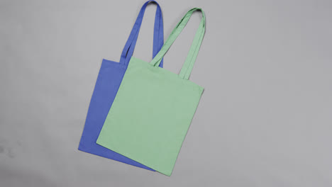 Nahaufnahme-Von-Blauen-Und-Grünen-Taschen-Auf-Grauem-Hintergrund,-Mit-Kopierraum,-Zeitlupe