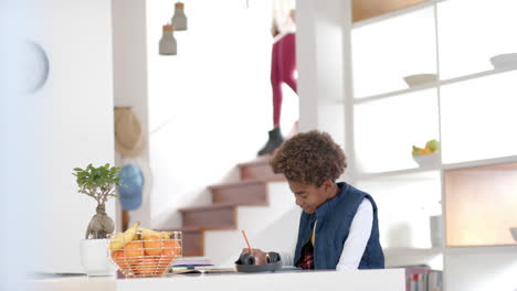African-american-boy-sitting-at-table-and-doing-homework,-slow-motion