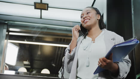 Fröhliche-Afroamerikanische-Geschäftsfrau,-Die-Im-Aufzug-Auf-Dem-Smartphone-Spricht,-Zeitlupe