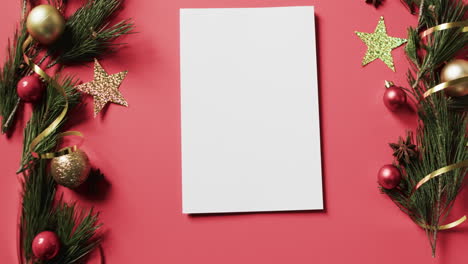 Video-of-christmas-decorations-and-white-card-with-copy-space-on-red-background