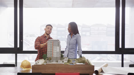 Diverse-male-and-female-architect-discussing-architectural-model-in-office,-slow-motion