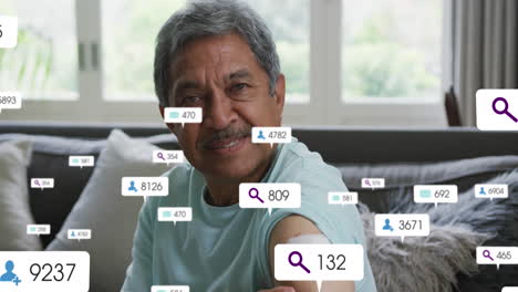 Animation-of-social-media-icons-and-numbers-over-senior-biracial-man-at-home