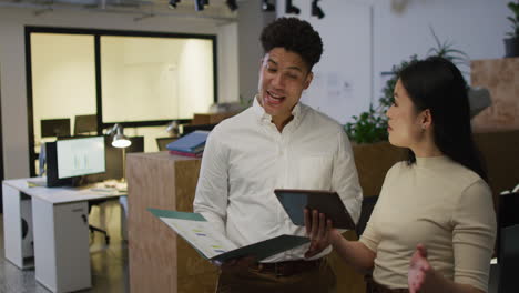 Biracial-man-and-Asian-woman-discuss-business-work-in-an-office