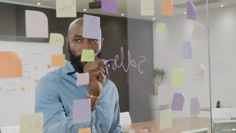 African-american-businessman-brainstorming,-making-notes-on-glass-wall-in-office-in-slow-motion