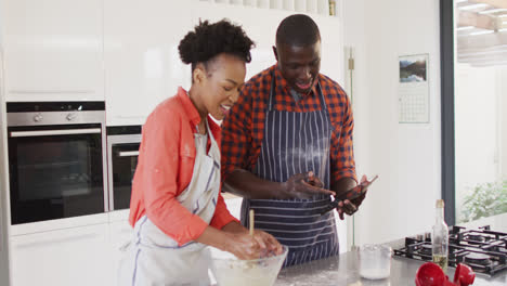Video-of-happy-african-american-couple-baking-together-in-kitchen