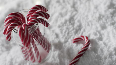 Video-of-christmas-candy-canes-in-jar-and-copy-space-on-snow-background
