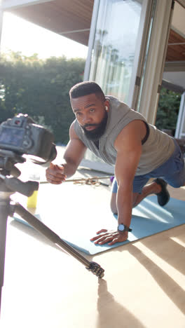 Vertical-video-of-african-american-male-fitness-vlogger-exercising-and-filming-at-home,-slow-motion