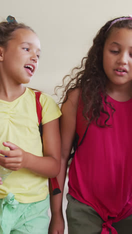 Video-of-happy-diverse-girls-walking-at-school-corridor-and-talking