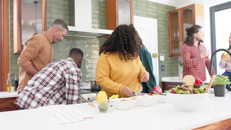 Happy-diverse-male-and-female-friends-preparing-food-together-in-kitchen