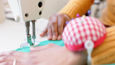 Biracial-female-fashion-designer-sewing-fabric-with-sewing-machine-in-studio,-slow-motion