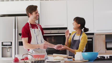 Video-of-happy-diverse-couple-baking-together-in-kitchen