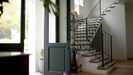 General-view-of-staircase-at-home-with-open-front-door,-slow-motion