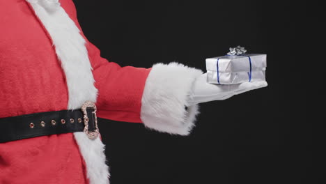 Video-of-santa-claus-holding-christmas-present-with-copy-space-on-black-background
