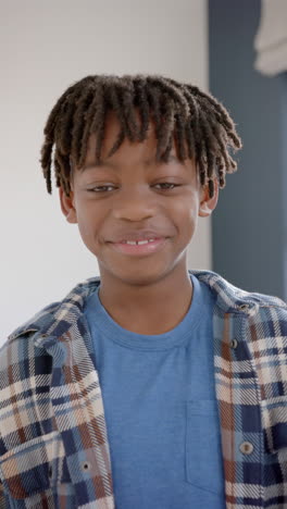 Vertical-video-of-portrait-of-happy-african-american-boy-smiling-at-home,-slow-motion