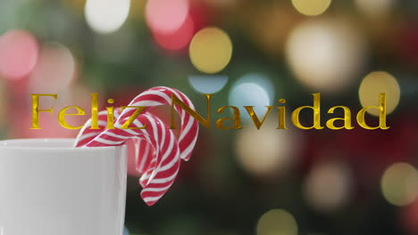 Feliz-navidad-text-in-gold-over-candy-canes-and-bokeh-christmas-lights